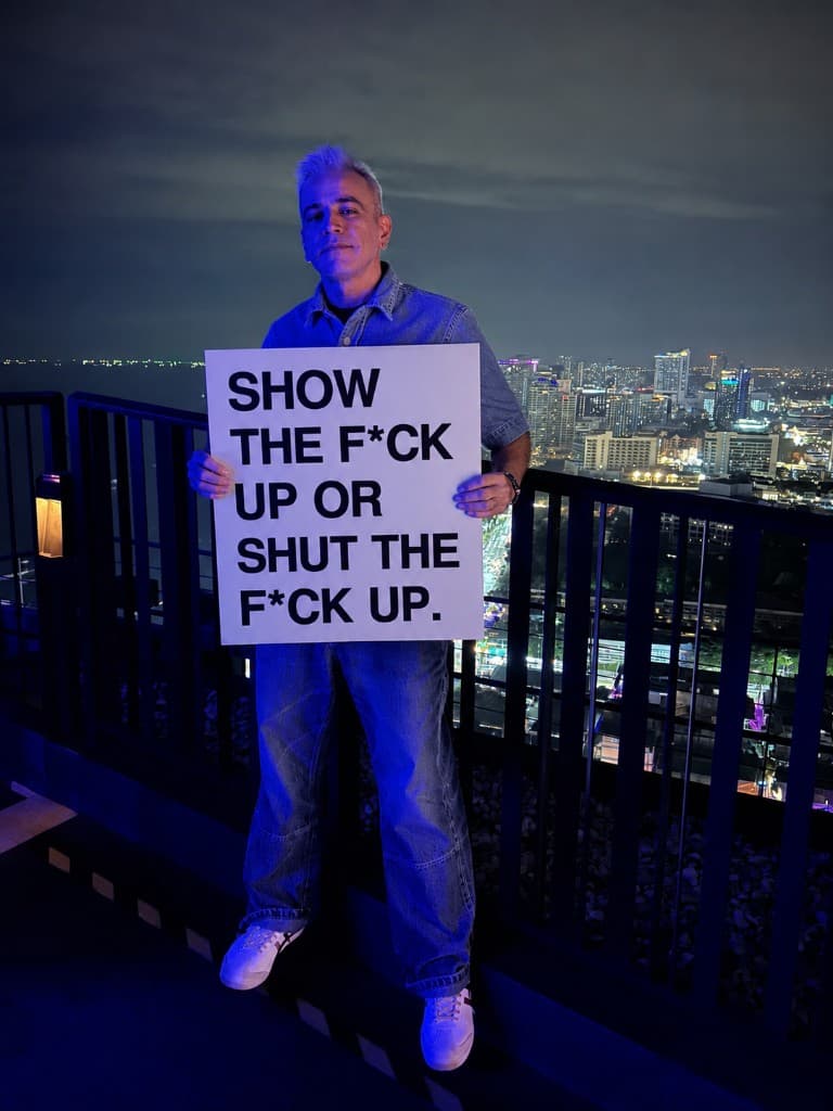 Rohan Bajaj holding a sign that reads: Show the f*ck up or shut the f*ck up.